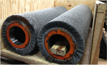 picture of two wide face abrasive bristle brush tubes for cleaning and finishing metal strip in a crate being built for shipping