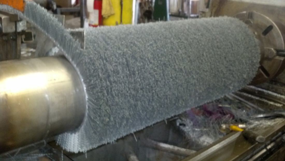 Picture of a wide face abrasive bristle brush being wound around a shaft