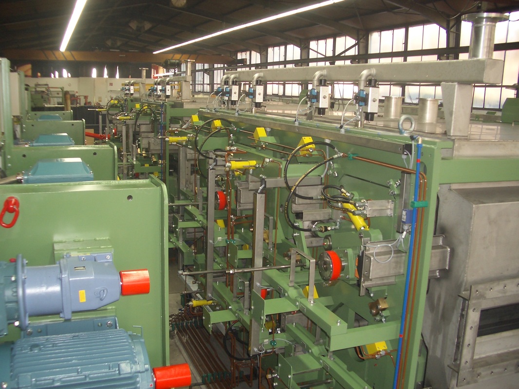 Picture of Inside the factory of many flat metal strip brush machines for cleaning and finishing wide strip metal with abrasive and/or non-abrasive brushes, show ease of brush quick change